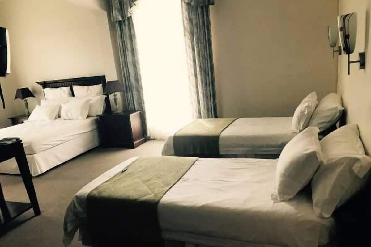 A hotel room with two single beds, a small desk, and a nightstand.