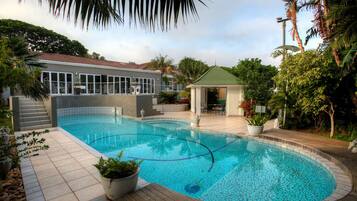 Relax by the serene pool surrounded by lush greenery and a patio.