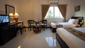 A hotel room with a bed, a desk with a television, two chairs, a small table with a vase, and a window with curtains. - Lao Golden Hotel (Vientiane)