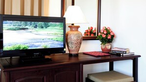 A television on a wooden desk with a vase of flowers and books. - Lao Golden Hotel (Vientiane)