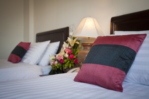 A neatly made bed with striped bedding and a decorative pillow. - Lao Golden Hotel (Vientiane)