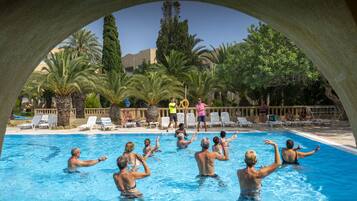 Un área de piscina con sillones de descanso y palmeras.