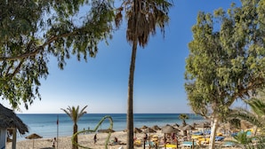 Une plage bordée de palmiers, avec des parasols et des chaises longues.