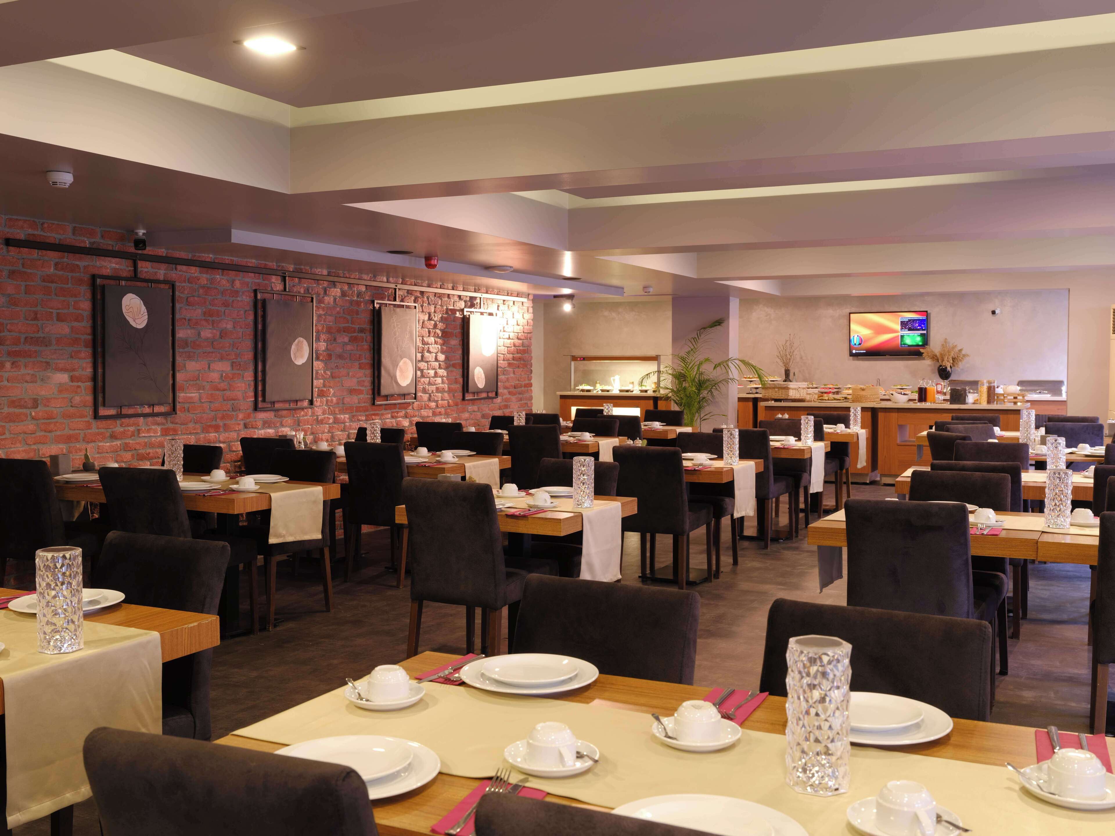 Ein Restaurant mit mehreren Tischen, Stühlen und einer Ziegelwand.