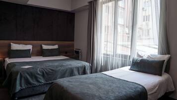 A hotel room with two beds, a large window with sheer curtains, and a dark wood headboard.