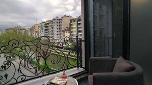 Un balcon donnant sur un paysage urbain, une chaise et une table avec des livres.