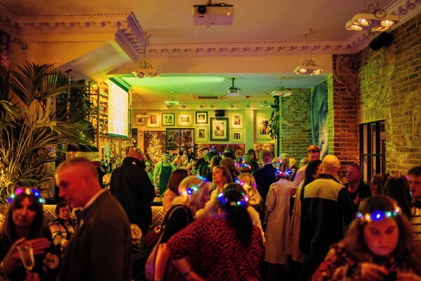 Un événement en intérieur très fréquenté, avec de nombreuses personnes, un bar et un éclairage décoratif.