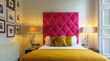 Una habitación de hotel con una cama grande, un cabecero rojo y cuadros enmarcados en la pared.