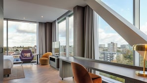 A modern hotel room with a large window, a bed, a desk, and a chair. - Corendon Amsterdam New-West, a Tribute Portfolio Hotel (Amsterdam)
