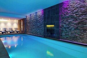 Ein moderner Poolbereich im Innenbereich mit Steinwand und Glasabtrennung.