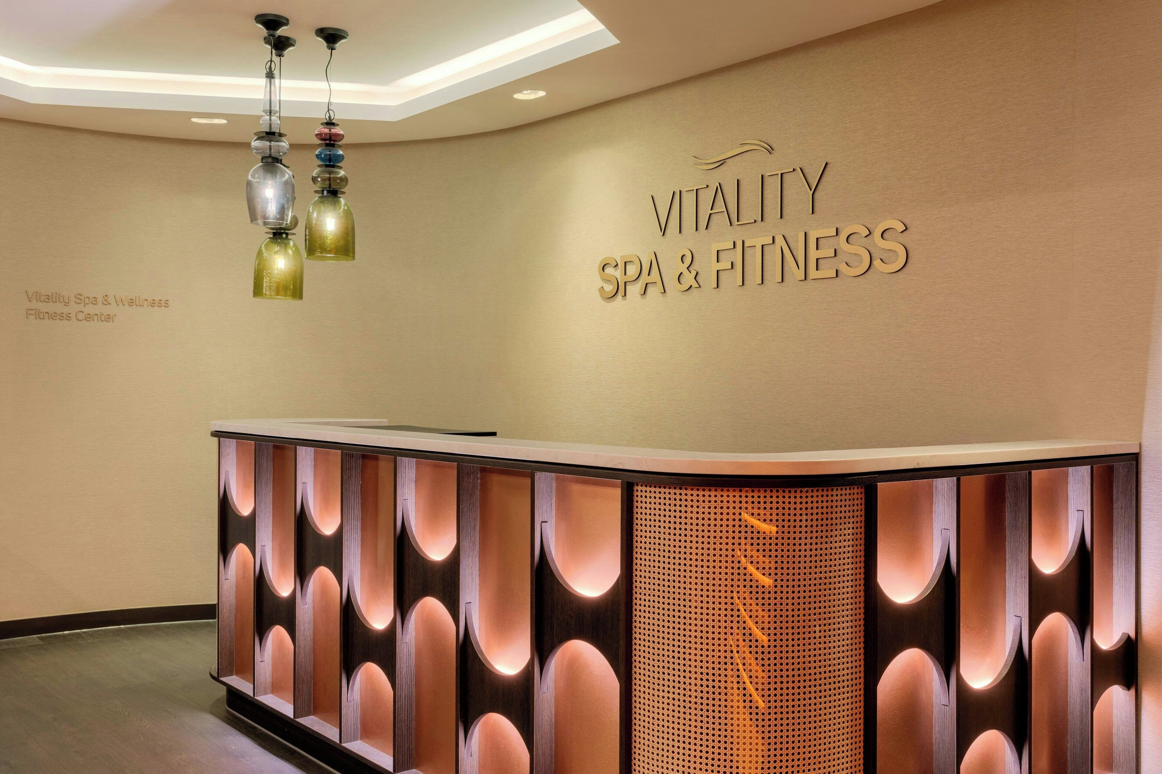 Een receptiegedeelte met een bord waarop 'Vitality Spa & Fitness' staat en een modern vormgegeven receptiebalie.