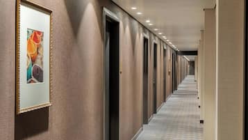 Un largo pasillo con puertas a un lado y un cuadro en la pared.