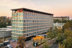 Ein modernes Hotelgebäude mit Glasfassade, mehreren Etagen und einer auffälligen Beschilderung oben.