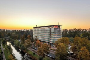 Ein mehrstöckiges Hotel mit modernem Design, umgeben von Bäumen und einem Fluss.