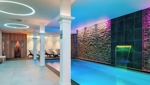 A modern indoor pool area with a stone wall and a glass enclosure. - Corendon Amsterdam New-West, a Tribute Portfolio Hotel (Amsterdam)