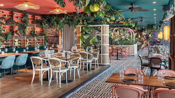 A restaurant with indoor plants, wooden tables, and chairs. - Corendon Amsterdam New-West, a Tribute Portfolio Hotel (Amsterdam)