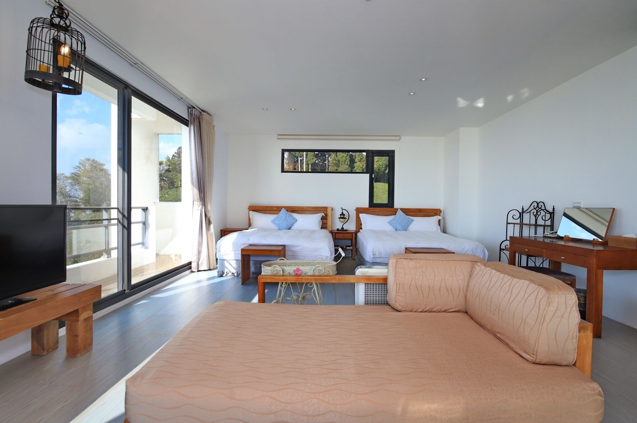 Un dormitorio con dos camas, un sofá grande, una televisión y un balcón con vistas.