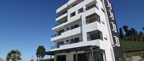 Un hotel de varios pisos con diseño moderno, que cuenta con balcones y ventanas amplias.
