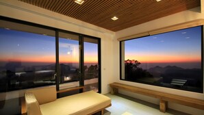 A modern room with a large window offering a sunset view, a sofa, and a bench. - Alishan B&B Yunmingi Aliscenery (Zhuqi)