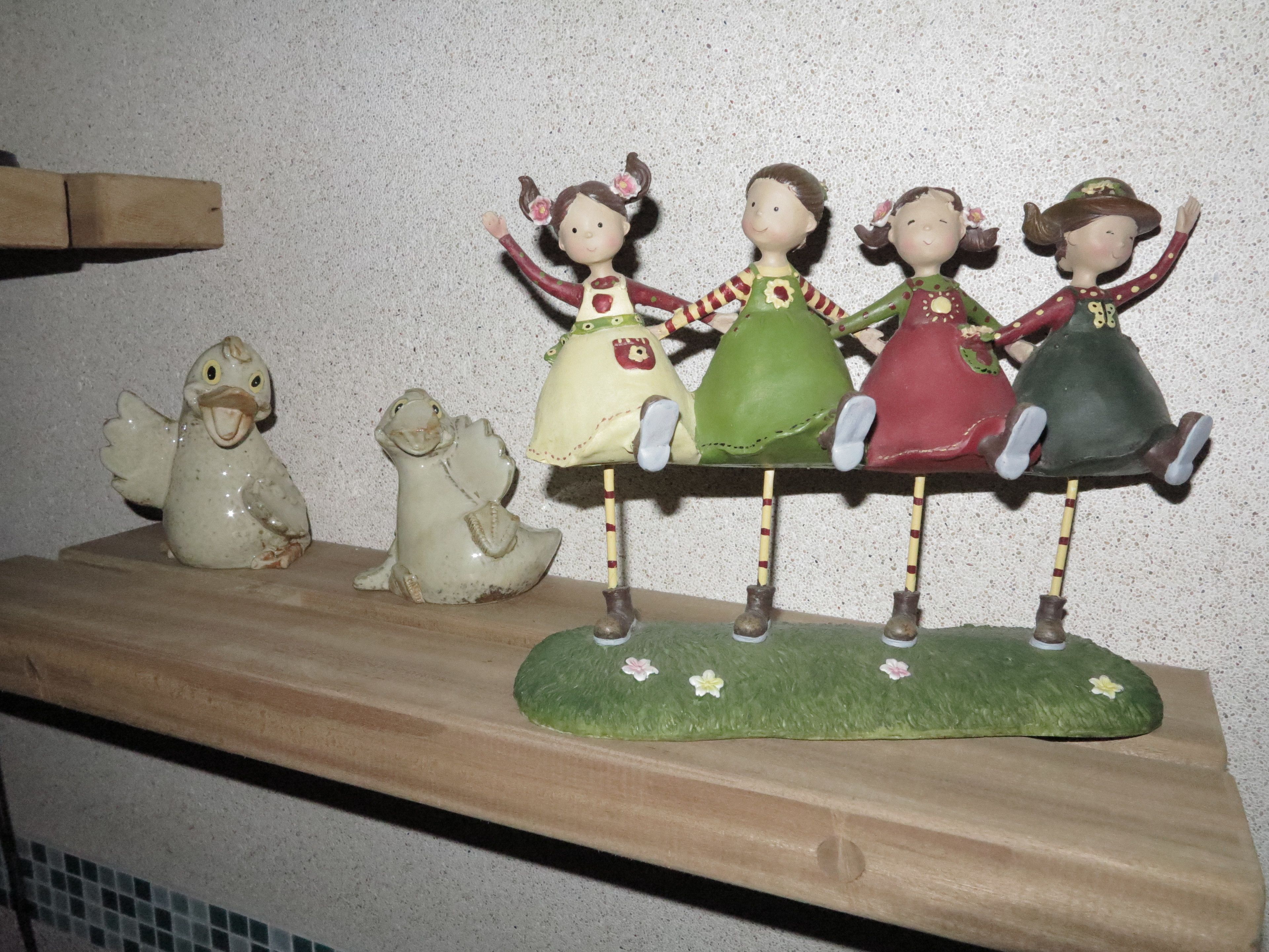 A shelf with ceramic figurines of children and a bird.
