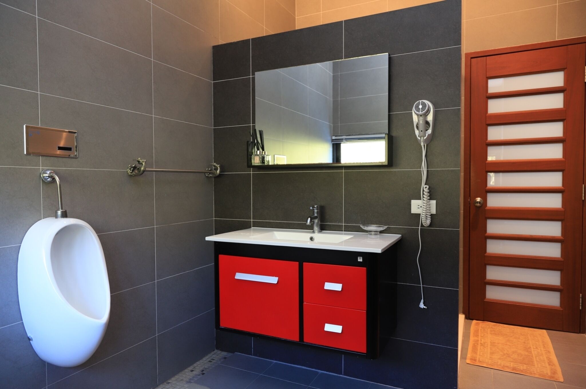 Une salle de bain moderne avec un urinoir, un lavabo et un miroir.