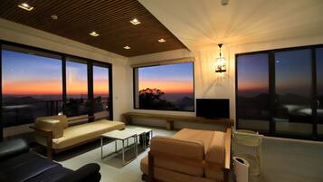 Una sala de estar moderna con ventanas amplias, un sofá, una mesa de centro y un televisor.