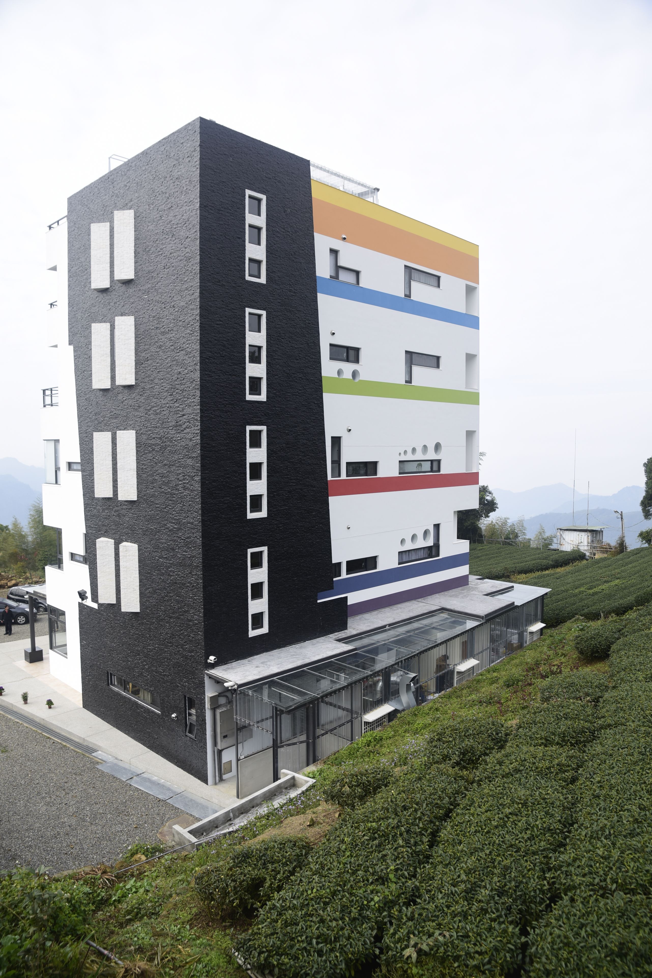 A modern multi-story building with a mix of black and white exterior walls, a flat roof, and a glass entrance.