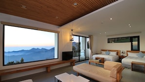 A modern hotel room with a large window offering a mountain view, a sofa, two beds, a TV, and a wooden ceiling. - Alishan B&B Yunmingi Aliscenery (Zhuqi)