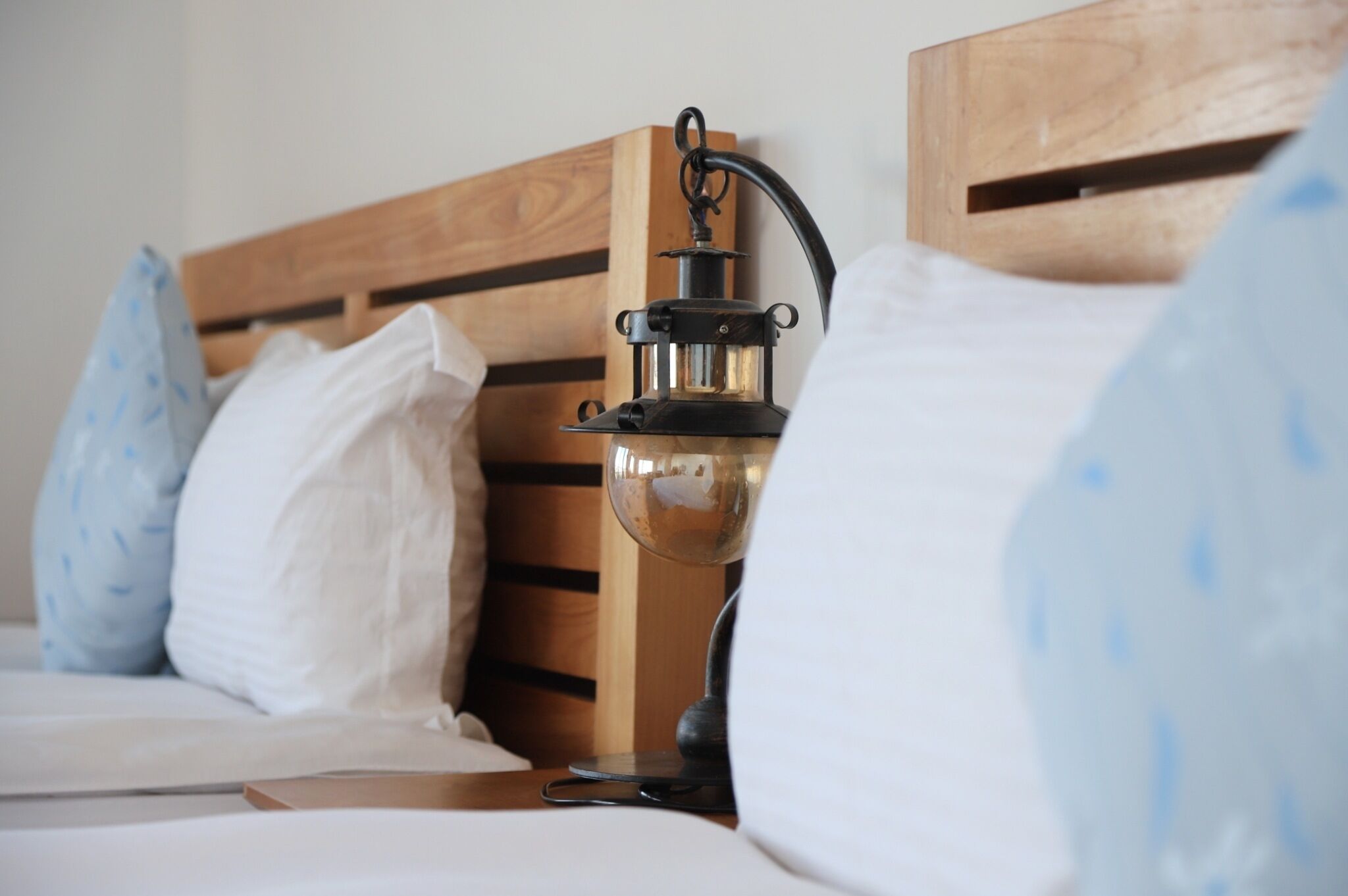A bed with a wooden headboard, a bedside table with a lamp, and a pillow.