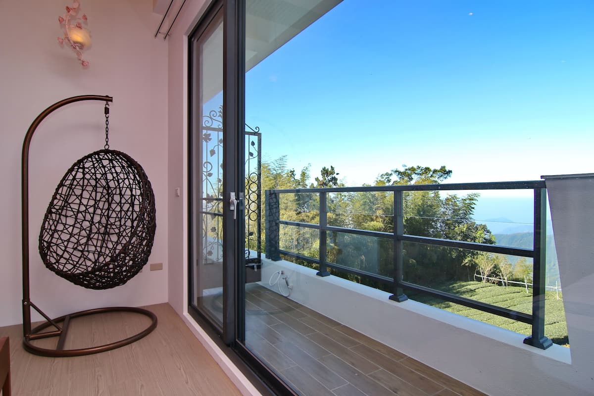 Un balcon donnant sur un paysage verdoyant, avec un fauteuil suspendu.