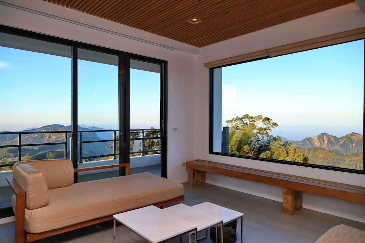 Une chambre moderne avec un canapé, un banc et une grande fenêtre donnant sur les montagnes.