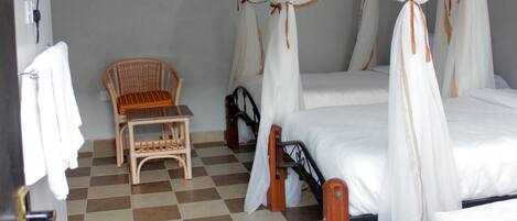 A room with a checkered floor, a bed with a canopy, a chair, and a small table.