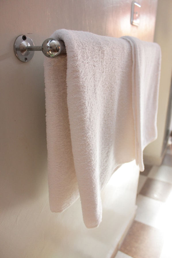 A white towel hanging on a metallic towel rack attached to a wall. - Sweet Lake Resort (Naivasha)