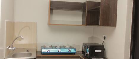 A compact kitchen with a sink, a stove, and a microwave.