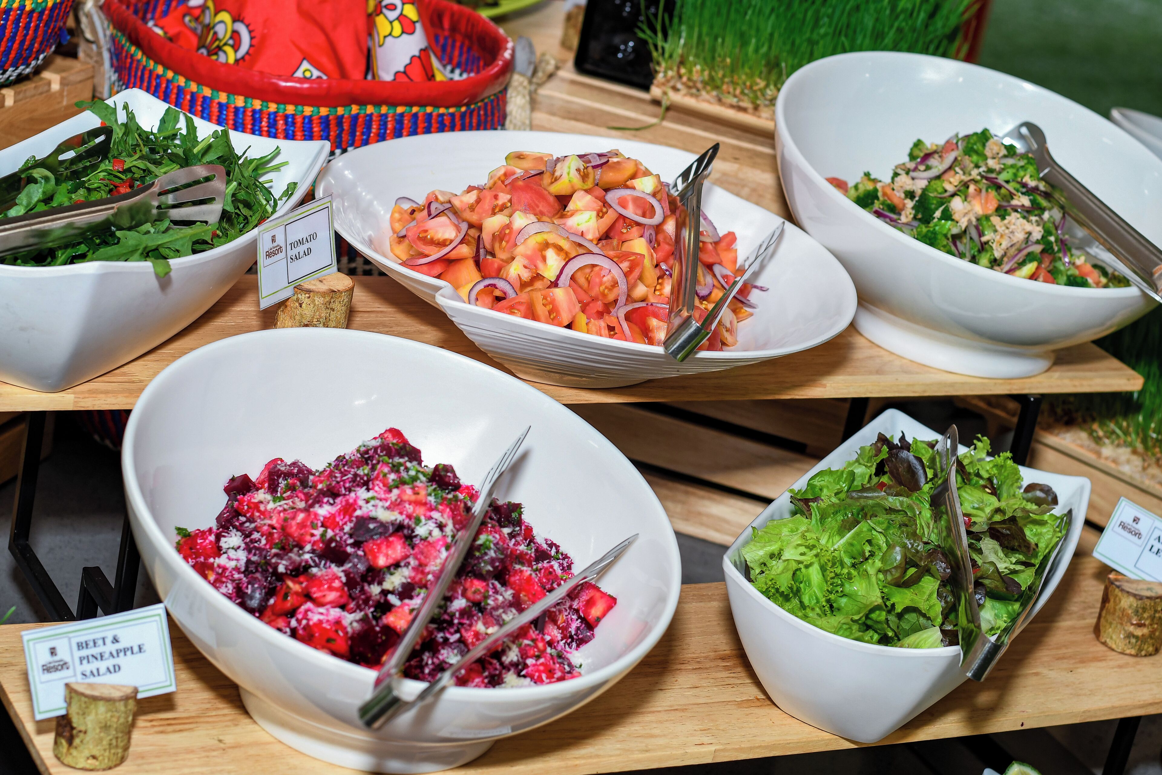 A buffet with various salads and a sign indicating a beet and pineapple salad.