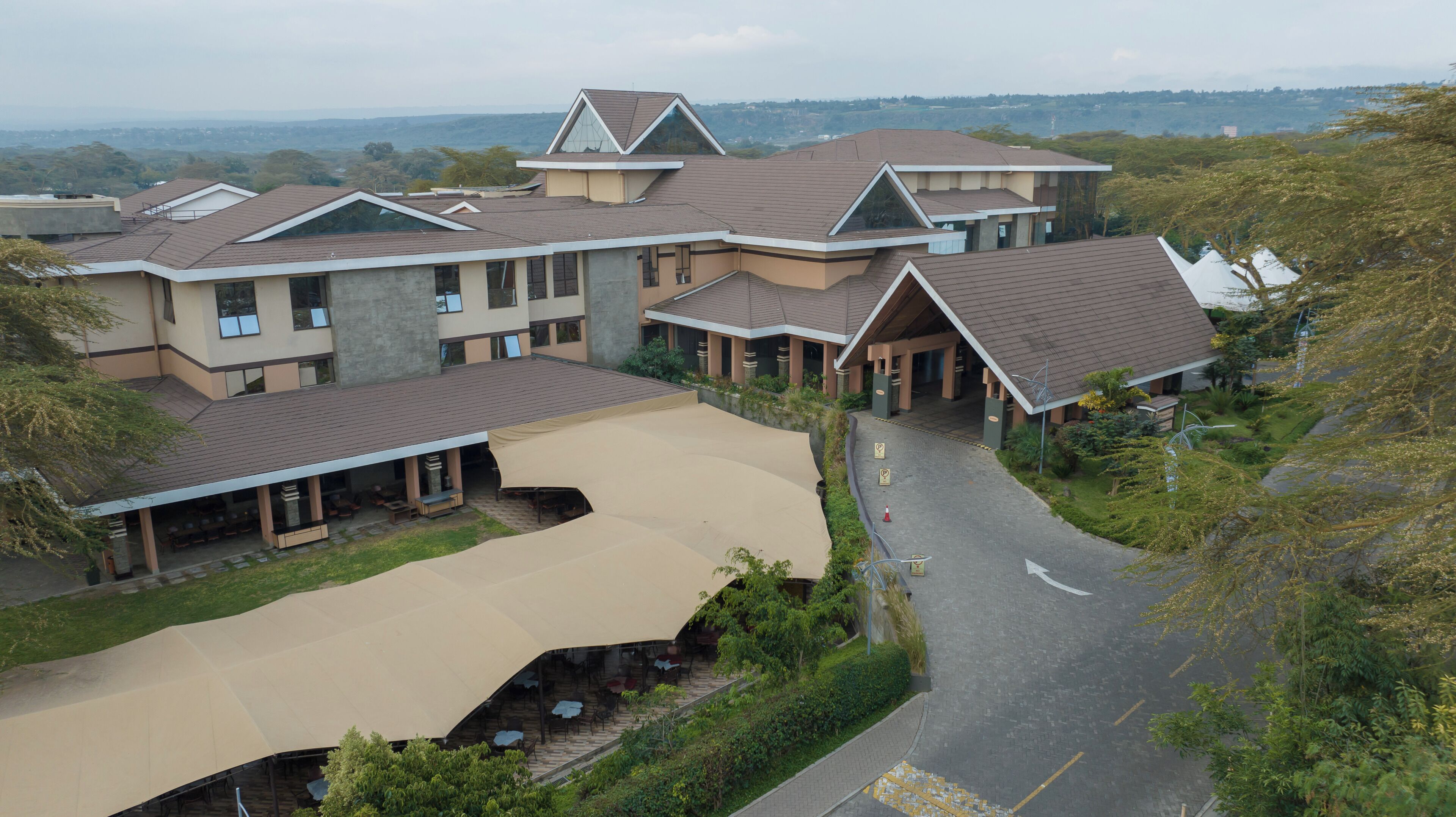 A multi-story hotel with a covered outdoor seating area and a view of the surrounding landscape.