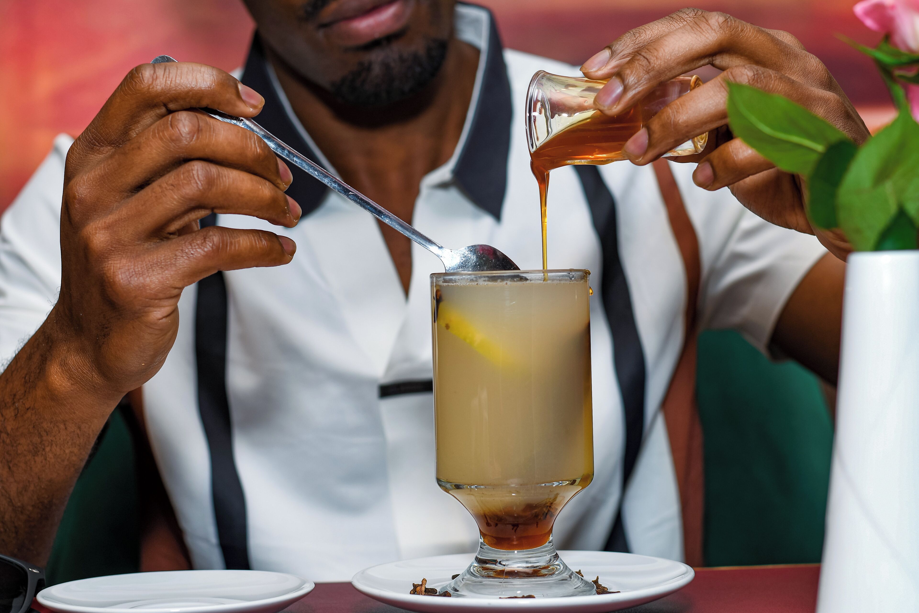 A person pouring a drink into a glass with a spoon.