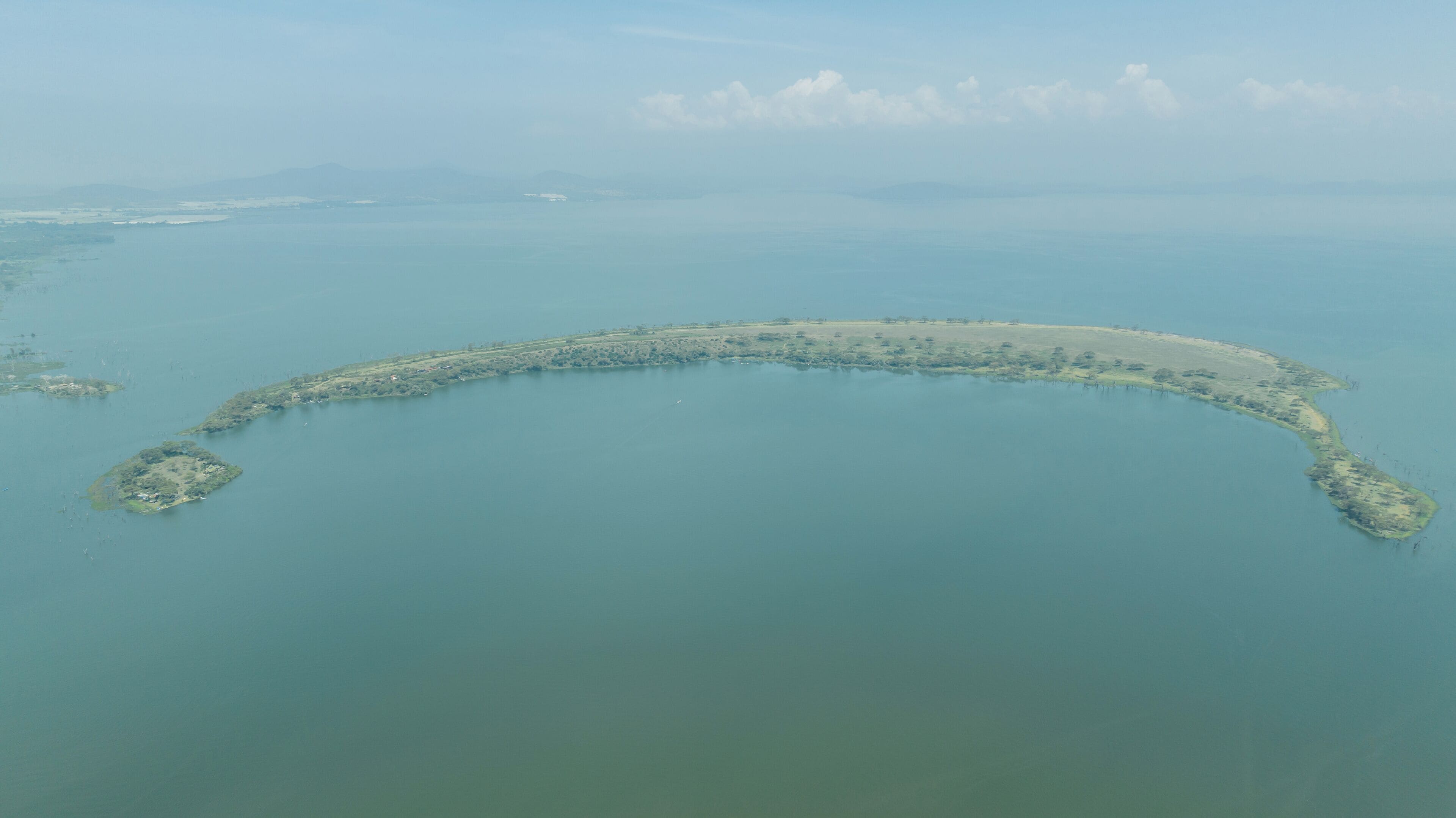 Una vista aerea di un’isola costiera con una linea di costa curva, immersa in acque calme.