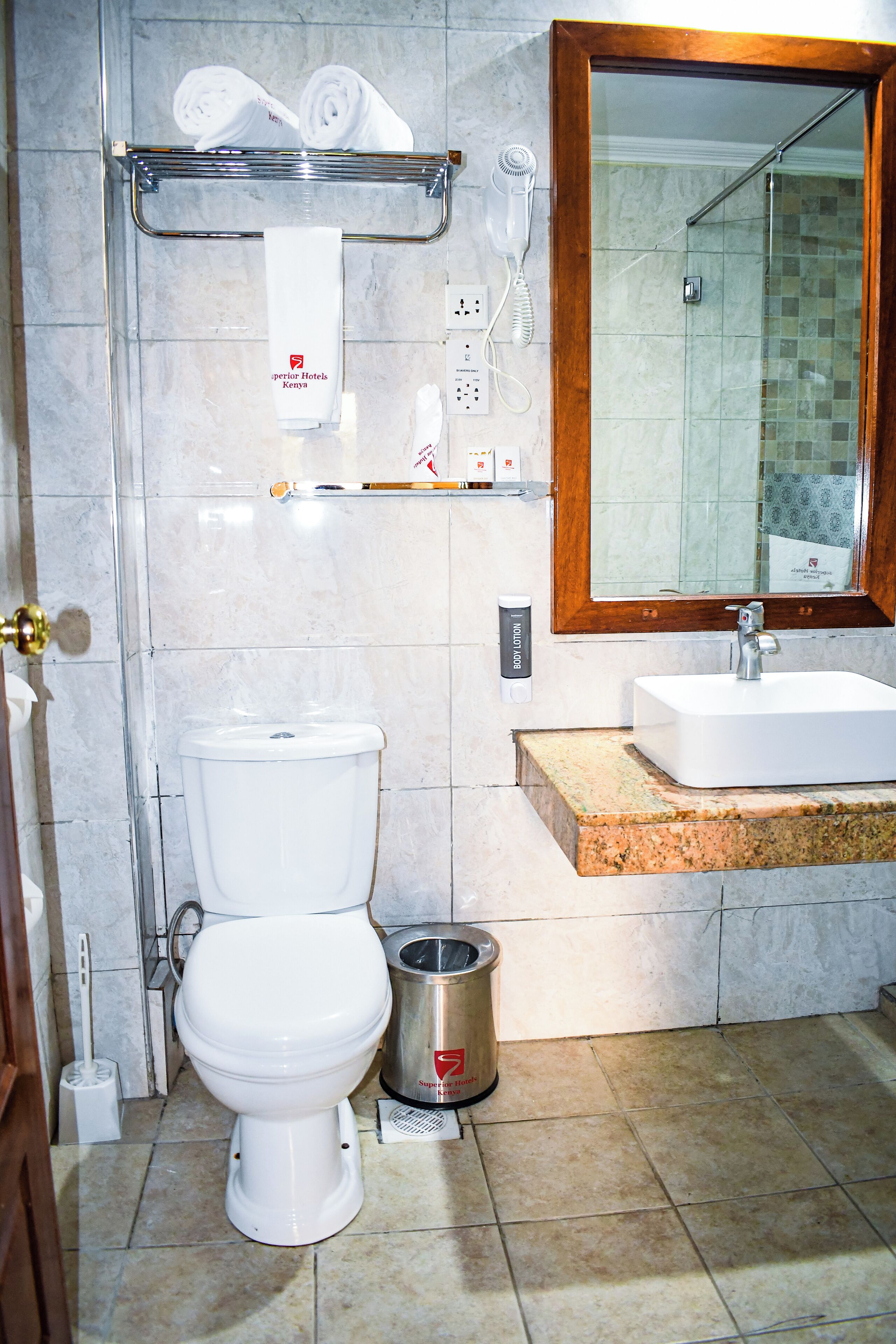 A bathroom with a toilet, a sink, a mirror, and a shower area.