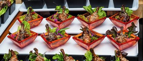 A variety of dishes arranged in black and red square containers, likely part of a buffet or dining setup.