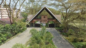 L’entrée du complexe hôtelier Lake Naiyasha, avec un chemin dégagé menant au bâtiment principal, est entourée d’une végétation luxuriante.