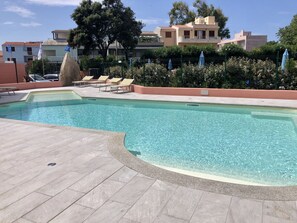 A swimming pool with clear water, surrounded by lounge chairs and a stone deck. - Residence I Mirti Bianchi (Santa Teresa di Gallura)