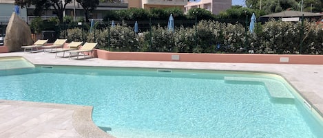 Una piscina al aire libre de temporada, sombrillas