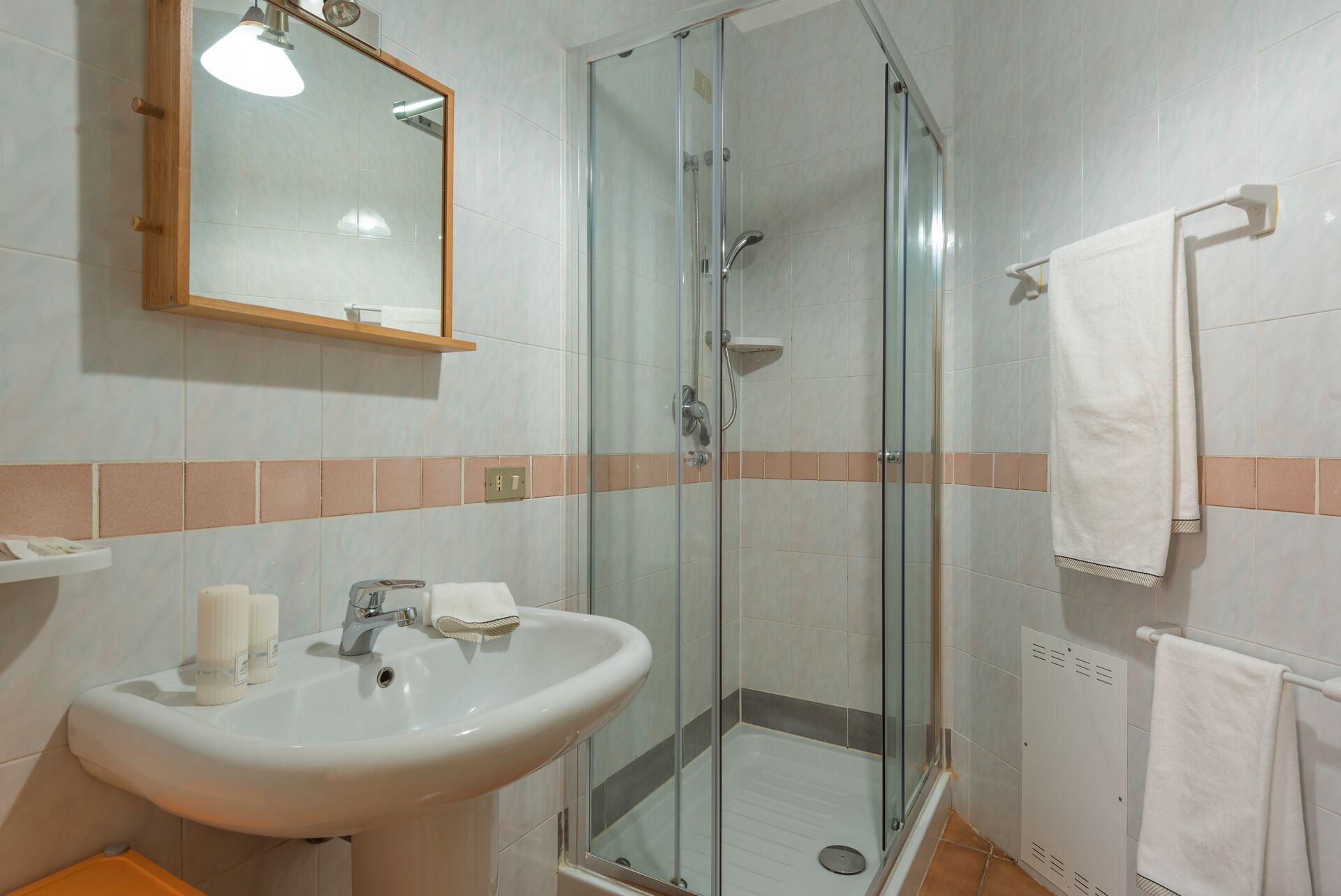 Ein Badezimmer mit einer Duschkabine, einem Waschbecken mit Spiegel darüber und einem Handtuchhalter.