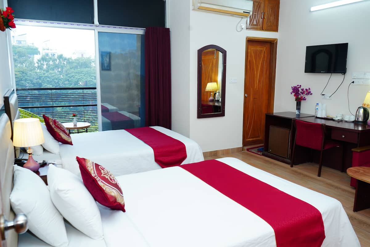 A hotel room with two beds, a desk, a TV, and a balcony with a view.