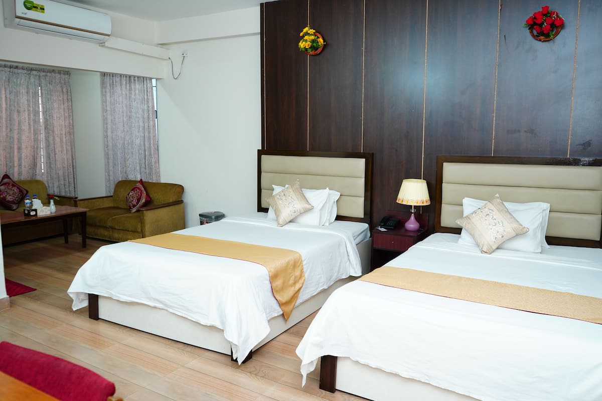 A hotel room with two beds, a sofa, a desk, and a mirror.