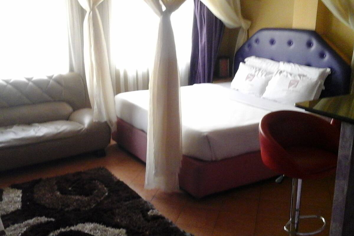 Un dormitorio con cama, sofá, sillón y alfombra.