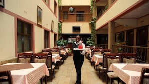 A restaurant with a central serving area and multiple tables with pink tablecloths. - Bienvenue Delta Hotel (Nairobi)