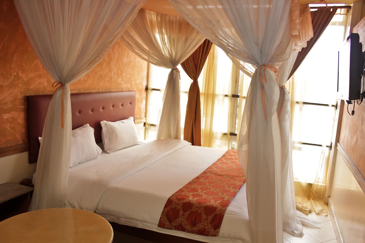 A bed with a canopy, a wooden headboard, and a bedside table.
