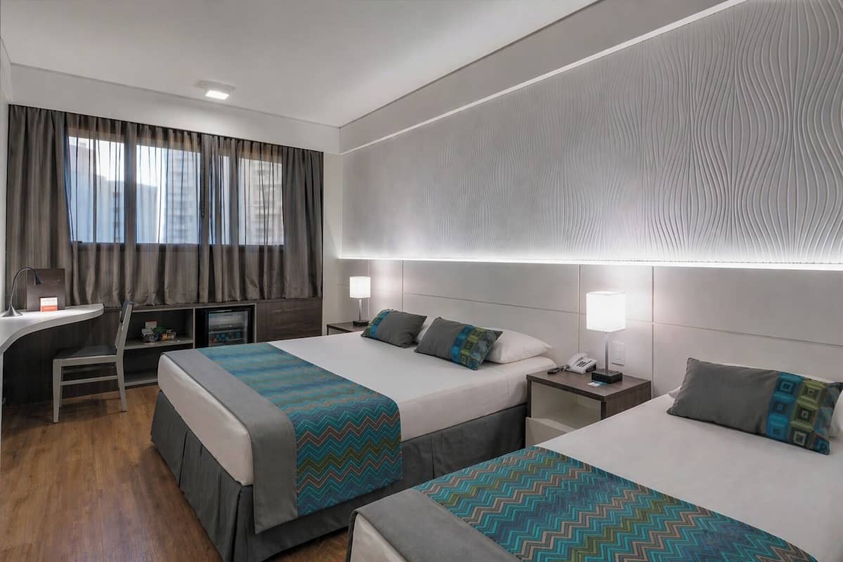 Ein Hotelzimmer mit zwei Betten, einem Schreibtisch und einem Stuhl.